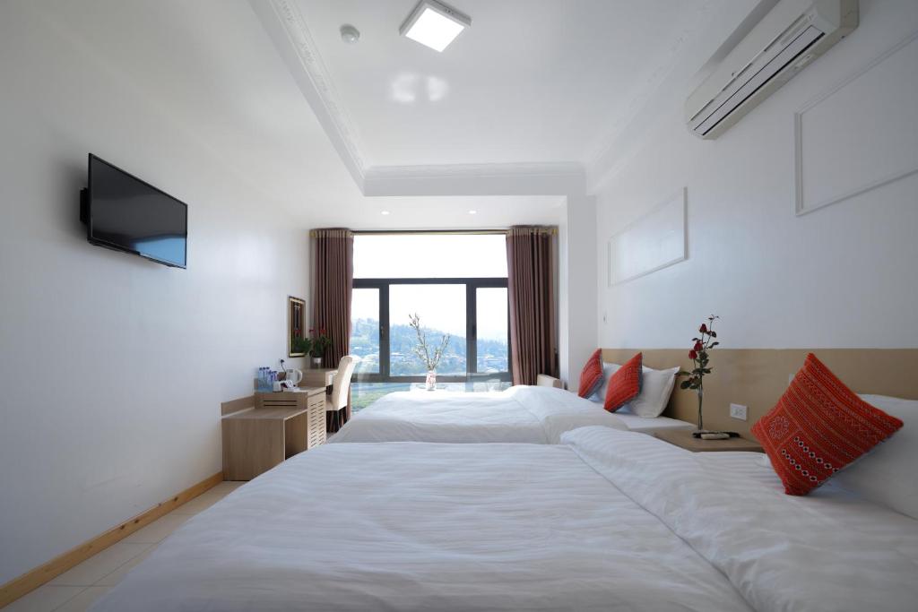 a bedroom with a large white bed and a television at Cong Fu Hotel in Bắc Hà