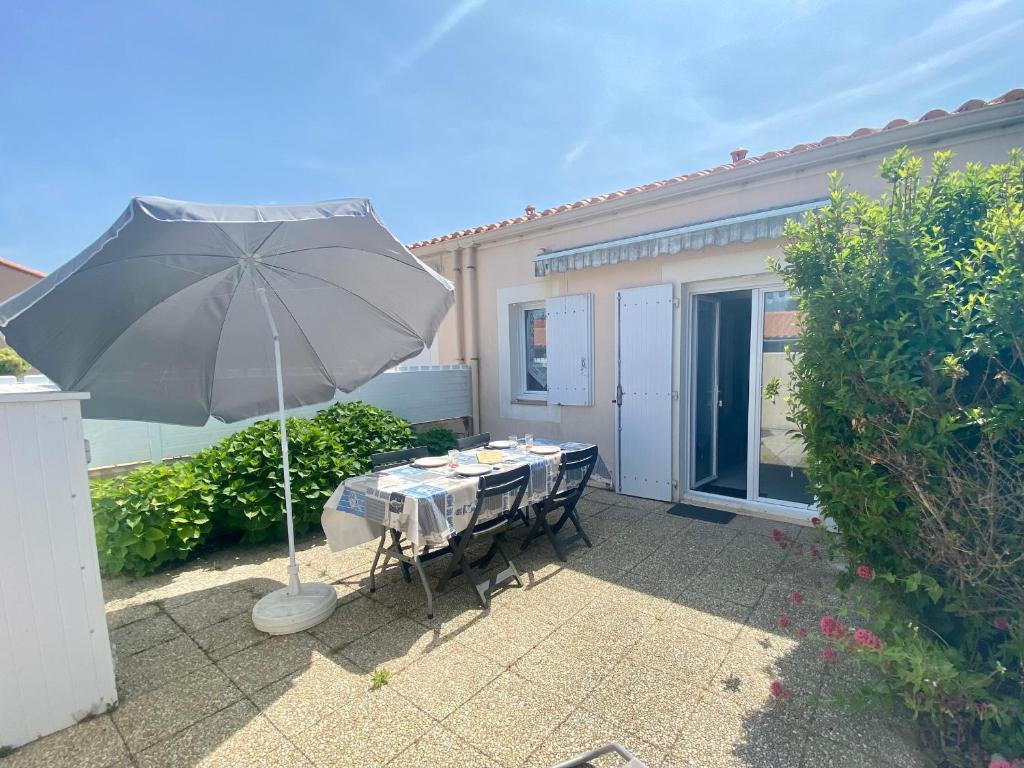 une table avec un parasol devant une maison dans l'établissement Maison Bretignolles-sur-Mer, 2 pièces, 4 personnes - FR-1-231-140, à Bretignolles-sur-Mer