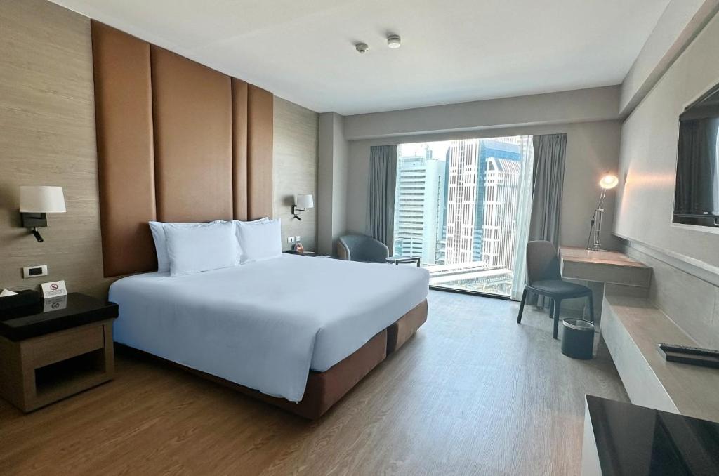 Ramada by Wyndham Bangkok Sukhumvit 11 في بانكوك: غرفة فندقية بسرير كبير ونافذة كبيرة