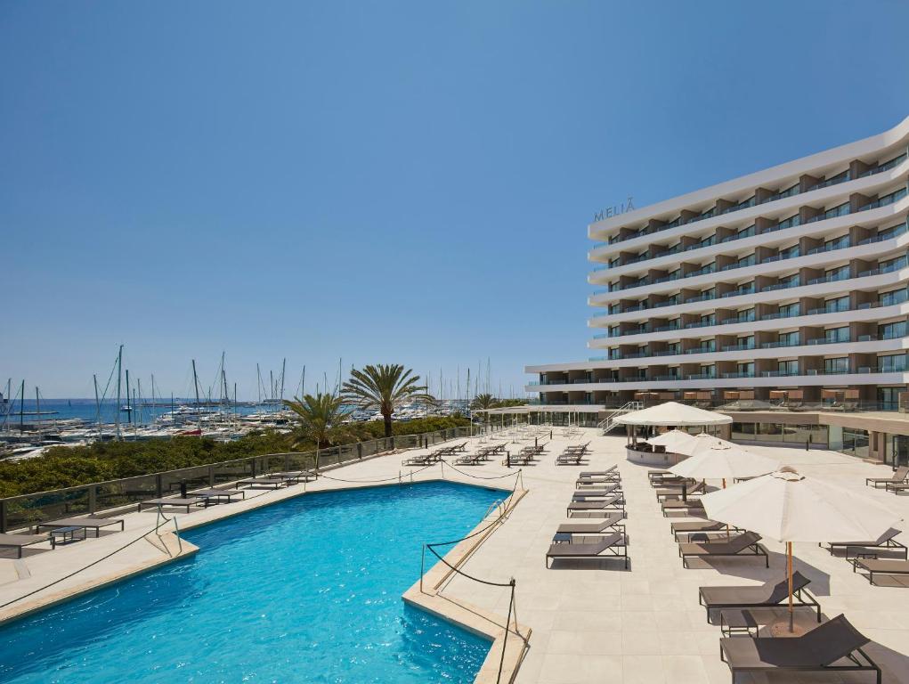 una piscina con sedie a sdraio e un grande edificio di Meliá Palma Marina a Palma de Mallorca