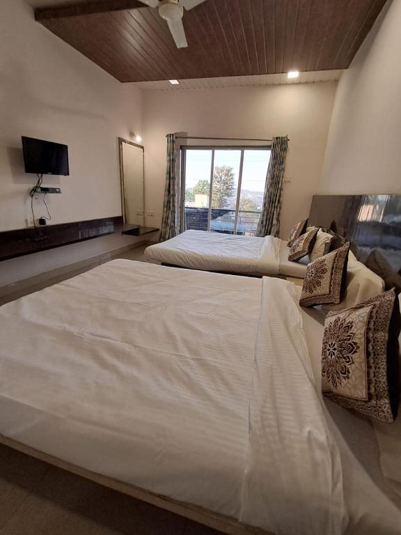 a large white bed in a room with a window at Tulsi Villa Bunglow in Mahabaleshwar