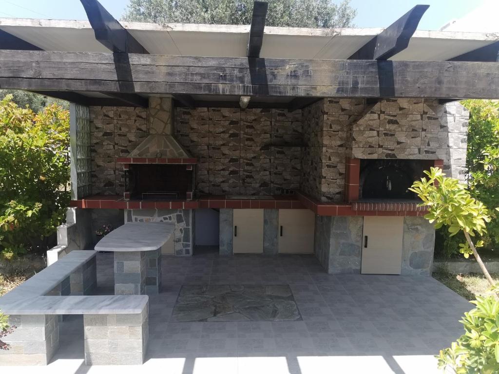 un patio con una chimenea de piedra y un banco en FOUNTAIN VILLA en Afantou