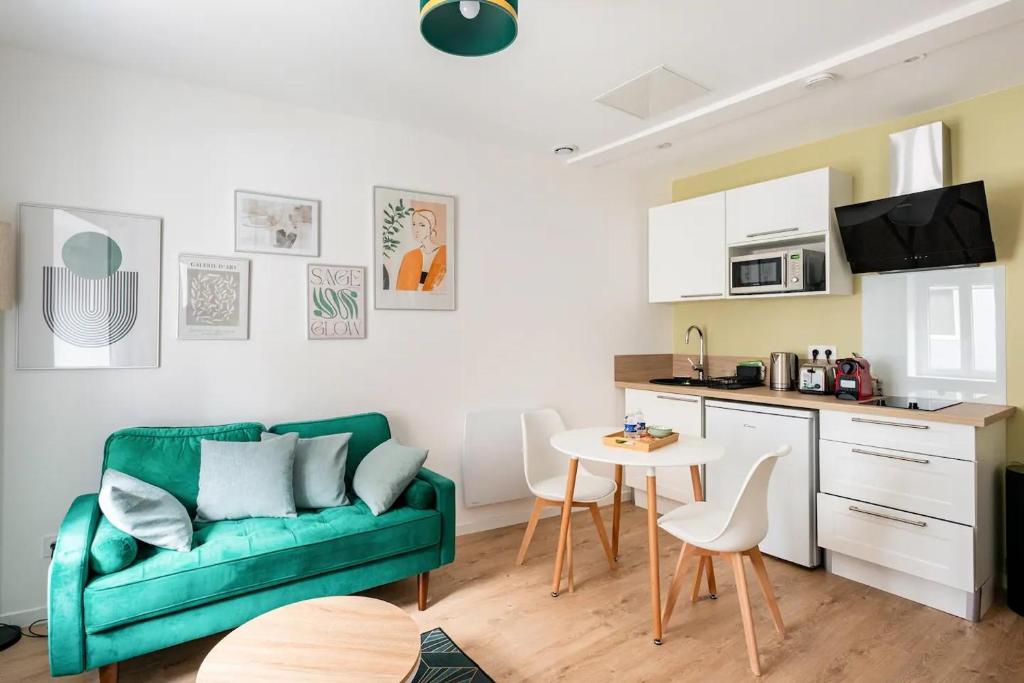 ein Wohnzimmer mit einem grünen Sofa und einem Tisch in der Unterkunft L'Ecrin Vert - 150m Restaurant 3 étoiles in Vonnas