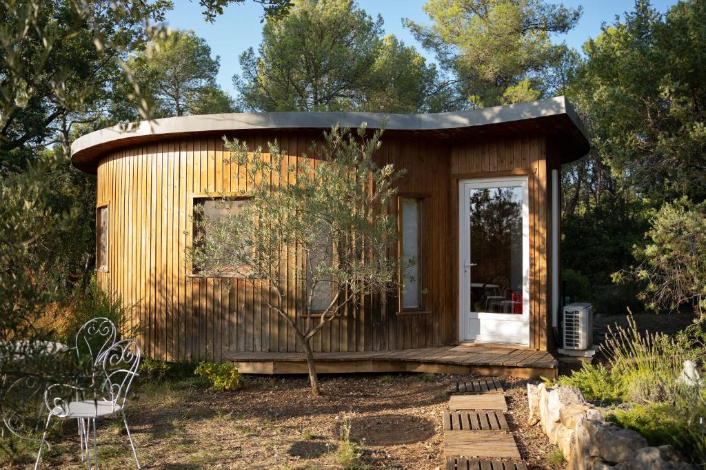 a small wooden cabin in a garden with a tree at Chalet dans plusieurs hectares de nature in Barjols