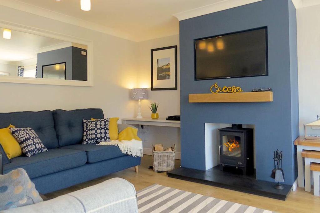 sala de estar con sofá azul y chimenea en Y Llofft Tresaith en Penbryn