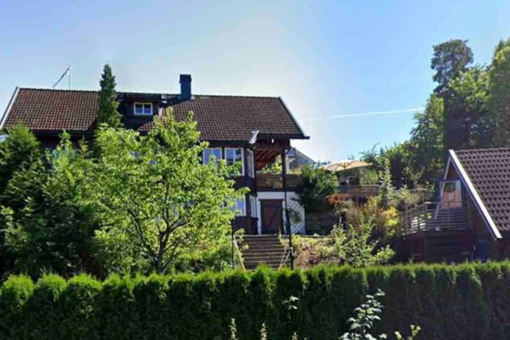 uma casa grande com uma cerca em frente em Sommerparadis på Nesbru - 5 min å gå til stranden em Asker