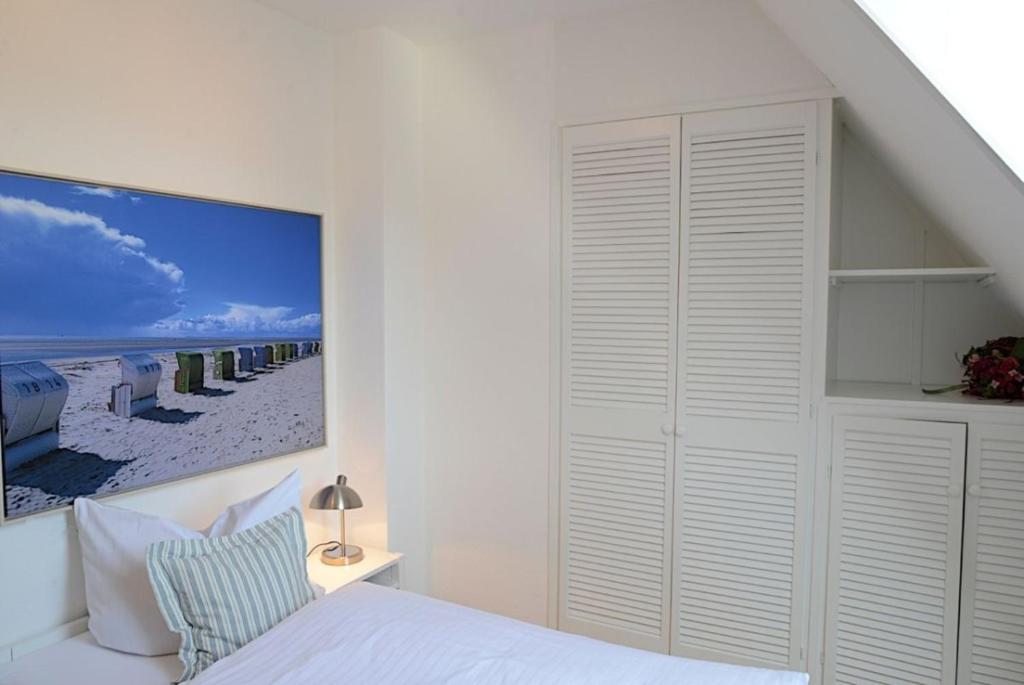 ヴィーク・アウフ・フェールにあるHaus Seeadler Whg 14の白いベッドルーム(ベッド1台付)とビーチの写真