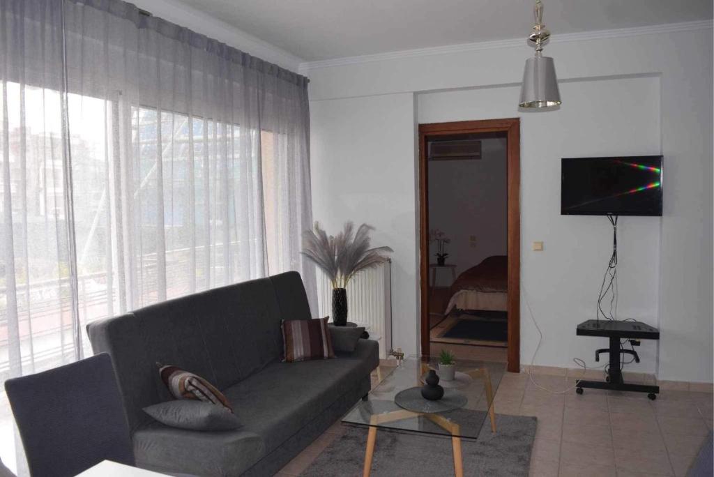 a living room with a couch and a large window at Shiny house near to sea @patra in Patra