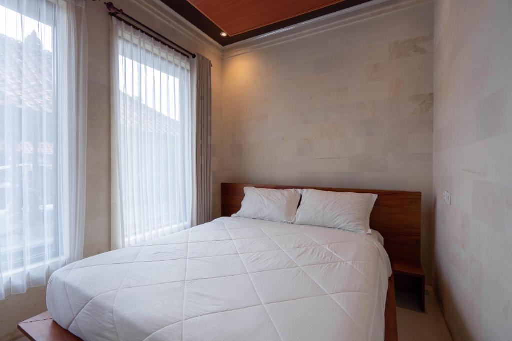 a bedroom with a large white bed and a window at Tebluess Gianyar in Bedahulu