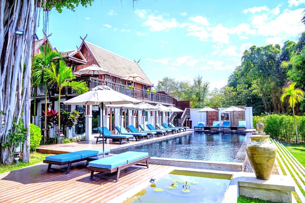 a pool at a resort with blue chairs and a building at Buri Sriping Riverside Resort & Spa - SHA Extra Plus in Chiang Mai
