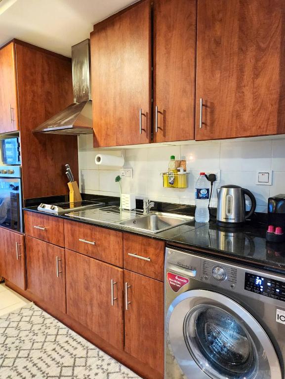 a kitchen with a washing machine and wooden cabinets at Rustic Elegance By The Lake Studio Cabin In Jlt in Dubai