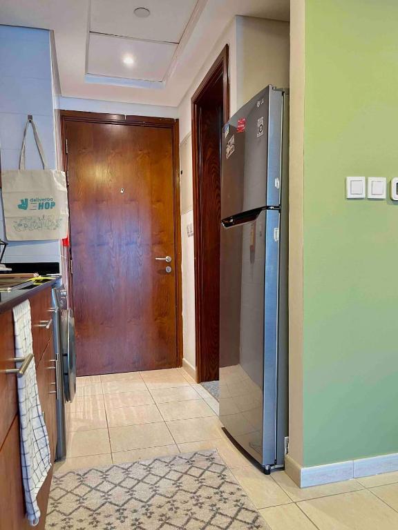 a kitchen with a refrigerator and a wooden door at Rustic Elegance By The Lake Studio Cabin In Jlt in Dubai