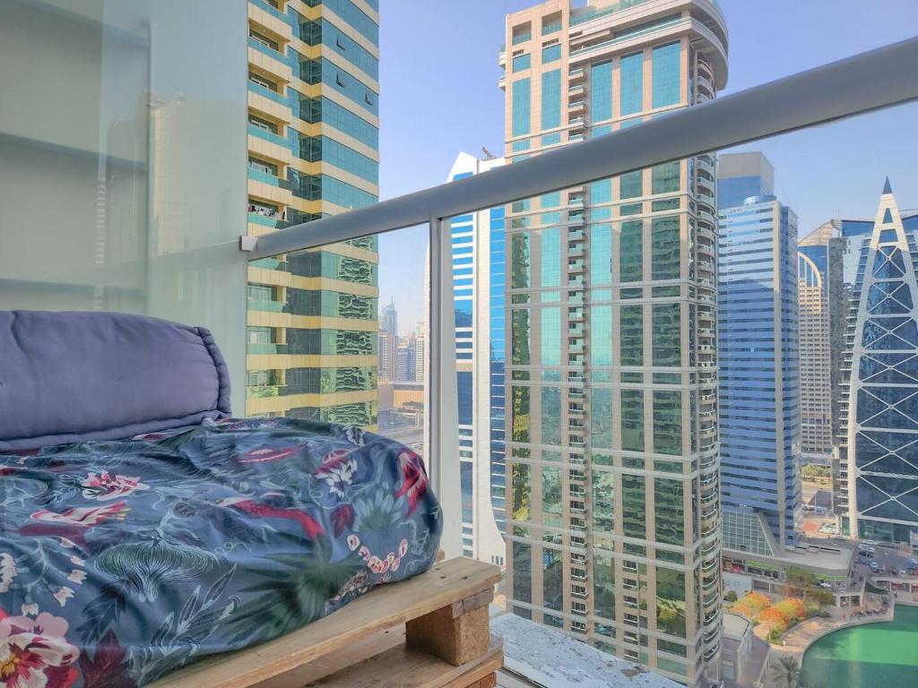 a bed on a balcony with a view of a city at Rustic Elegance By The Lake Studio Cabin In Jlt in Dubai