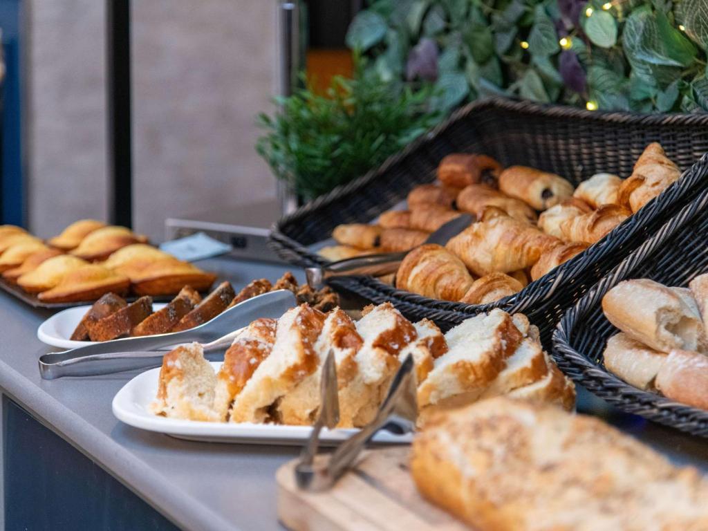 una mesa cubierta con platos de pan y bollería en ibis Paris Grands Boulevards Opéra 9e, en París