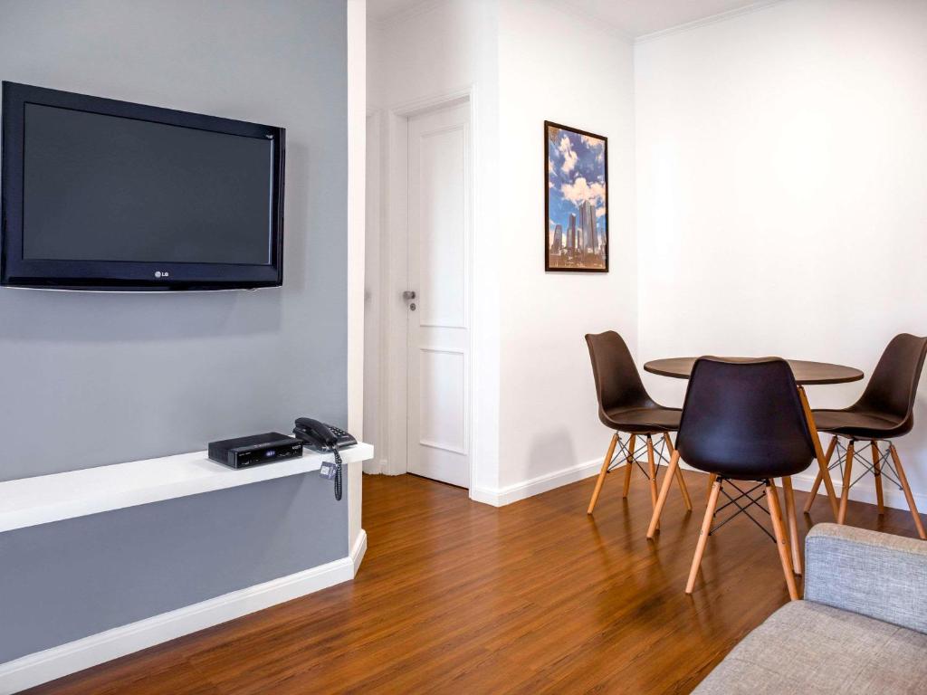 a living room with a table and a flat screen tv at Mercure Sao Paulo Berrini in Sao Paulo