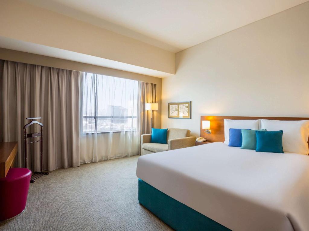 Novotel Deira Creekside Dubai في دبي: غرفة فندقية بسرير كبير ونافذة