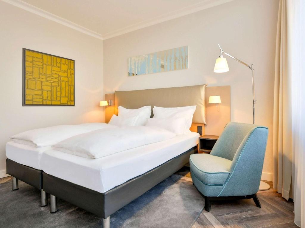 - une chambre avec un lit et une chaise bleue dans l'établissement Mercure Hotel Koeln Belfortstrasse, à Cologne