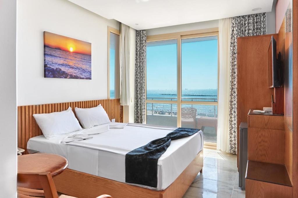 a bedroom with a bed with a view of the ocean at El Mena Grand in ‘Izbat al Burj