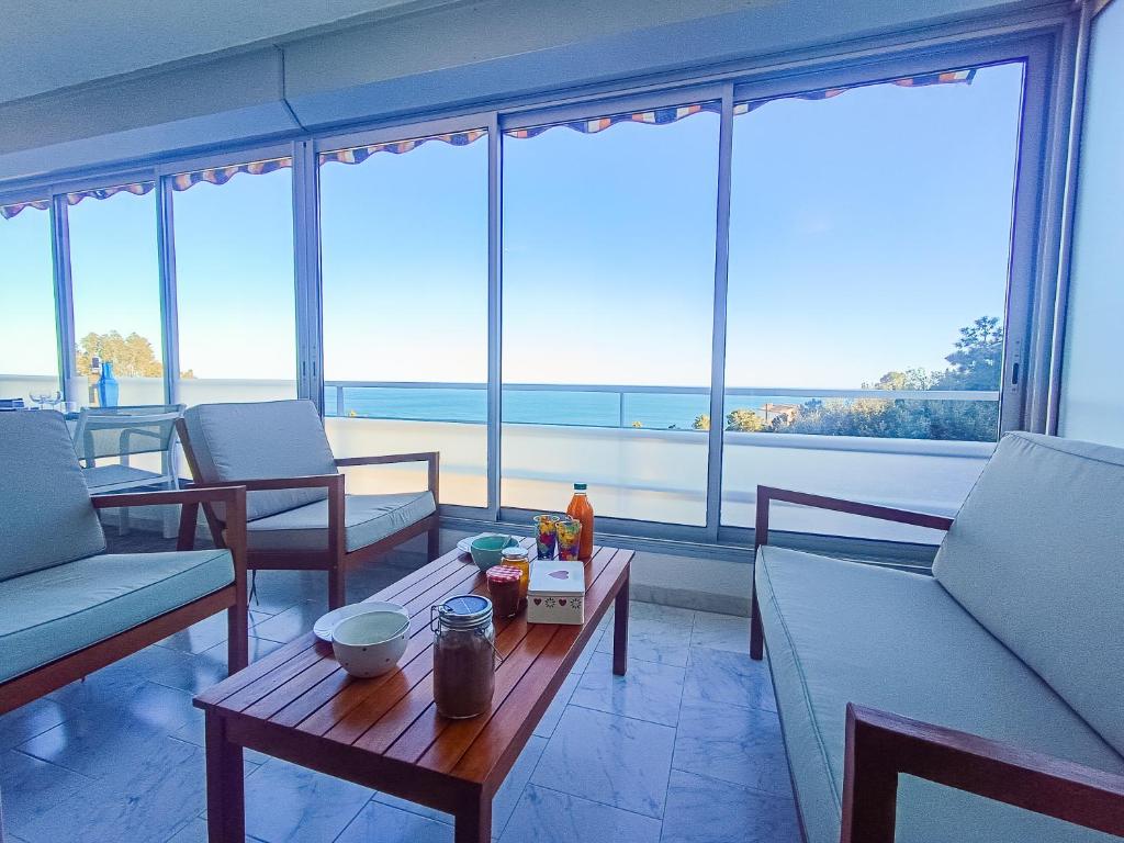 a living room with a table and chairs and large windows at Elégant 3 pièces vue mer - Roc - Les Clés de l'Esterel in Saint-Raphaël