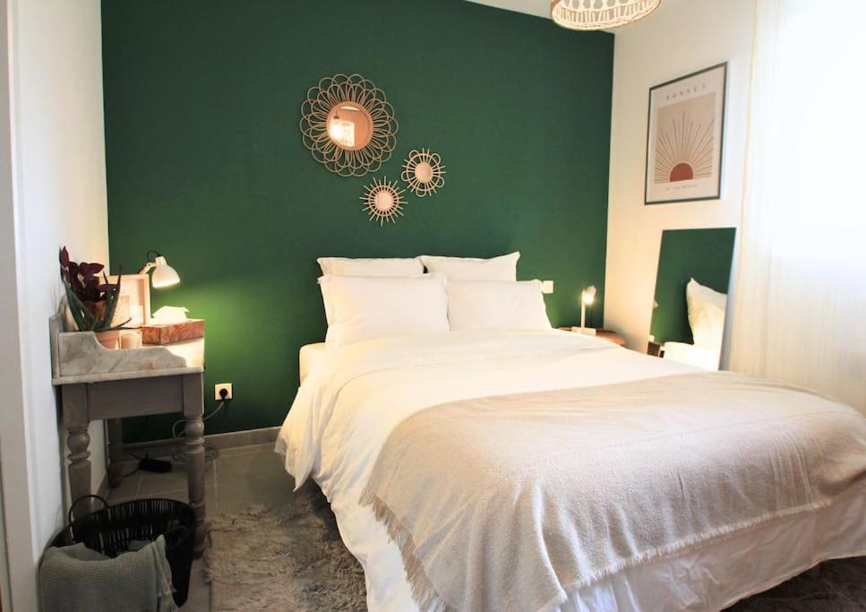 ein Schlafzimmer mit einer grünen Wand und einem weißen Bett in der Unterkunft Cosy appartement entre vignes et garrigue avec piscine in Péret