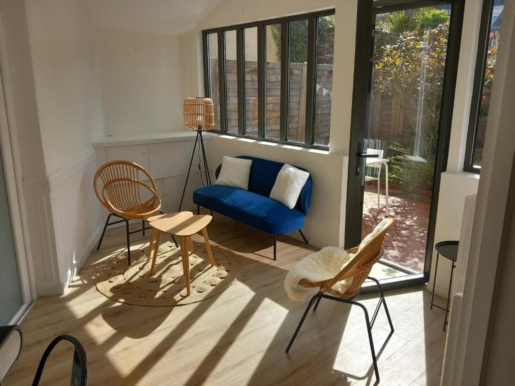 uma sala de estar com um sofá azul e cadeiras em Beau T3 avec jardin hyper centre proche gare em Angers