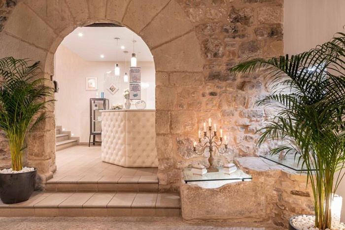 a lobby with a stone wall with two plants at Hotel PALACIO IVAN TARIN in Monteagudo del Castillo
