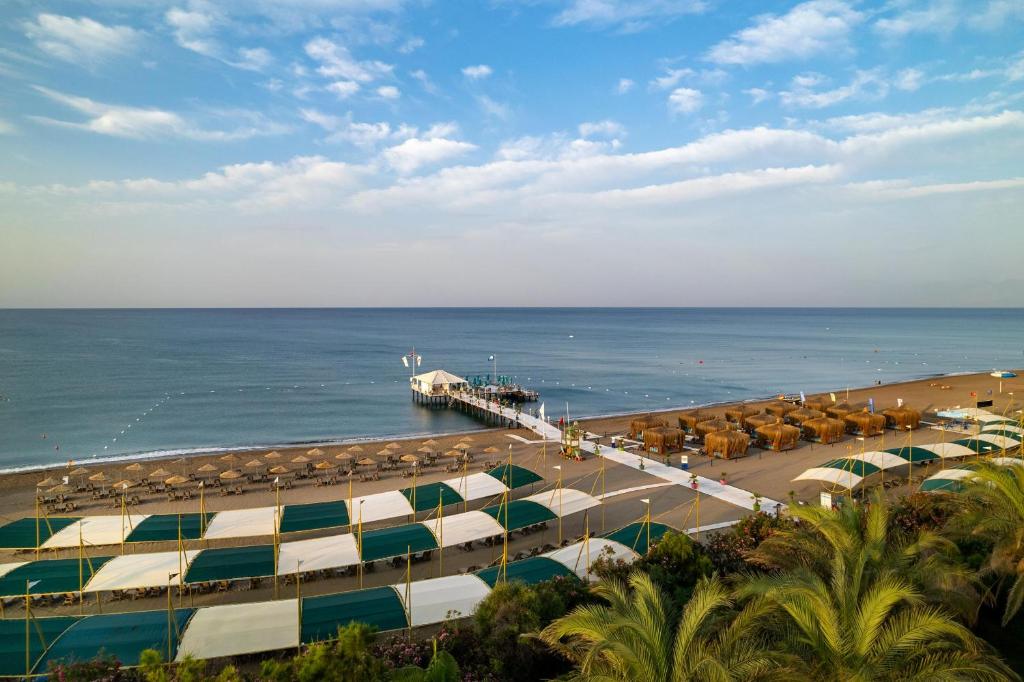 a beach with umbrellas and a pier with the ocean at Concorde De Luxe Resort - Prive Ultra All Inclusive in Lara