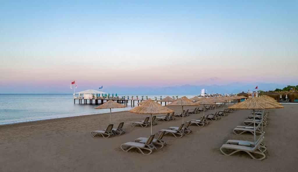 a row of chairs and umbrellas on a beach at Concorde De Luxe Resort - Prive Ultra All Inclusive in Lara