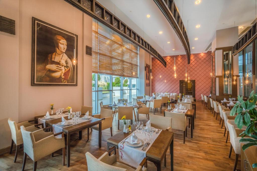 a restaurant with tables and chairs and a painting on the wall at Concorde De Luxe Resort - Prive Ultra All Inclusive in Lara