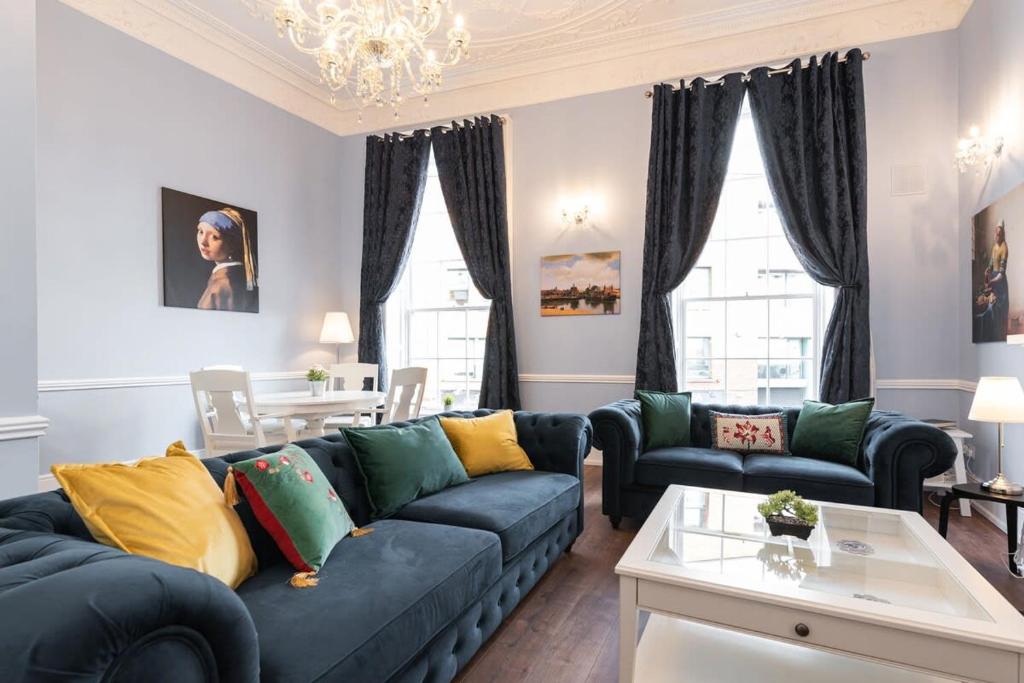 a living room with a blue couch and yellow pillows at 4 Poster Luxury Georgian Apartment in Dublin