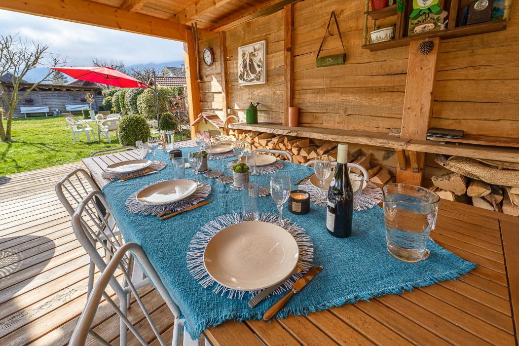a table with plates and wine glasses on a deck at Maison Ondine - Logement familial à deux pas du lac et des commerces in Saint-Jorioz