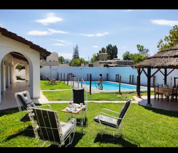 un patio con sillas, una mesa y una piscina en POSADA DE LA LUNA en Luján de Cuyo
