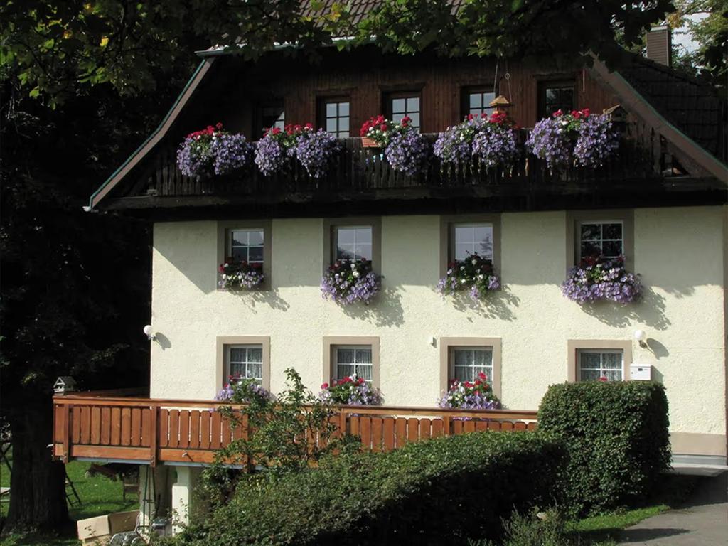 une maison blanche avec des boîtes de fleurs sur les fenêtres dans l'établissement Hirschlehaus - Ferienwohnung Seebachtal, à Hinterzarten
