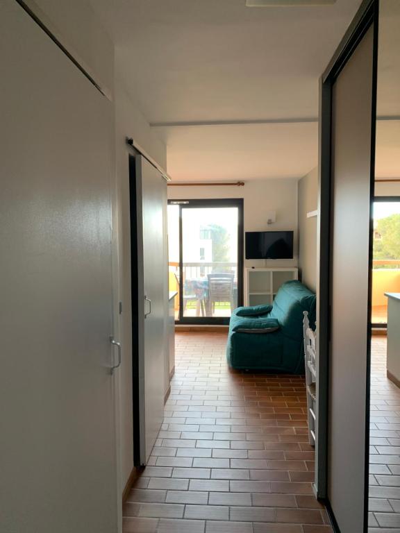 un soggiorno con divano verde e balcone di Appartement Domaine de la Coudouliere + piscine (mai à octobre) a Six-Fours-les-Plages