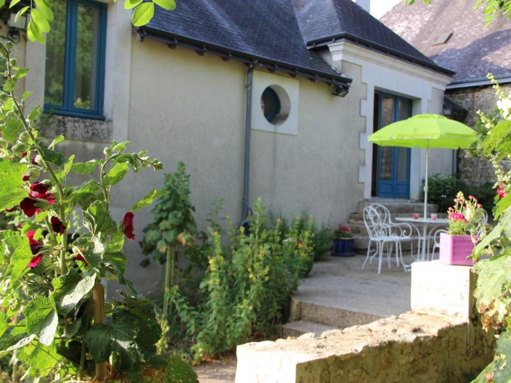 a house with a patio with a table and an umbrella at Gîte Cheillé, 3 pièces, 4 personnes - FR-1-381-68 in Cheillé