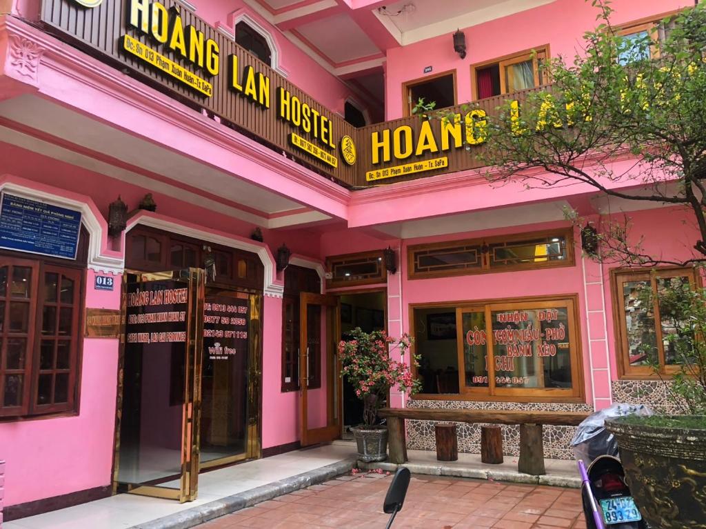 薩帕的住宿－Hoang Lan Hostel，粉红色的建筑,前面有标志