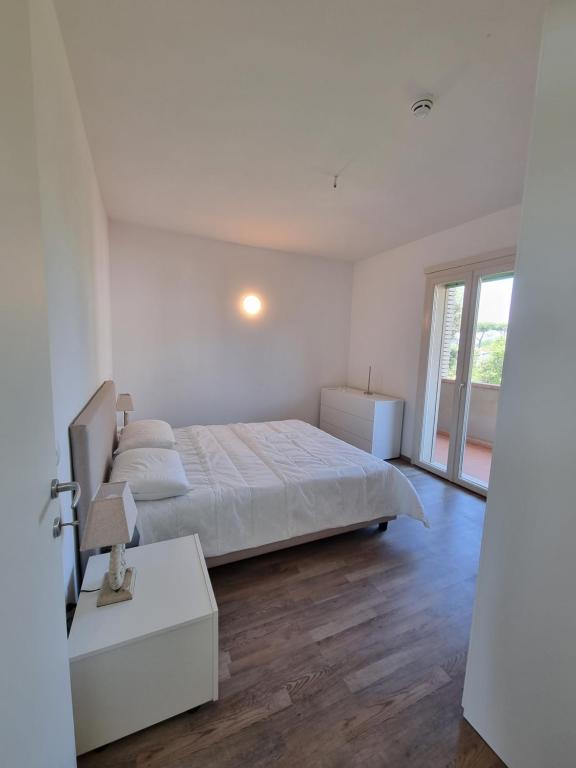 a white bedroom with a bed and a window at Residence San Francesco in Tirrenia