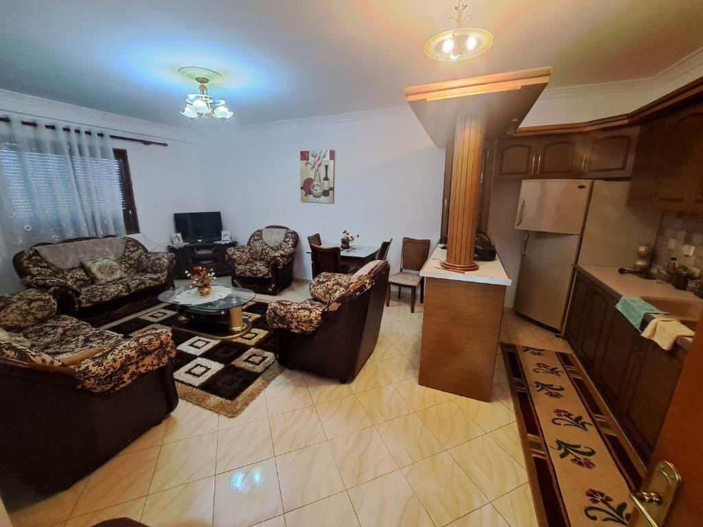 sala de estar con sofás, mesa y cocina en Apartament Miraka en Gramsh