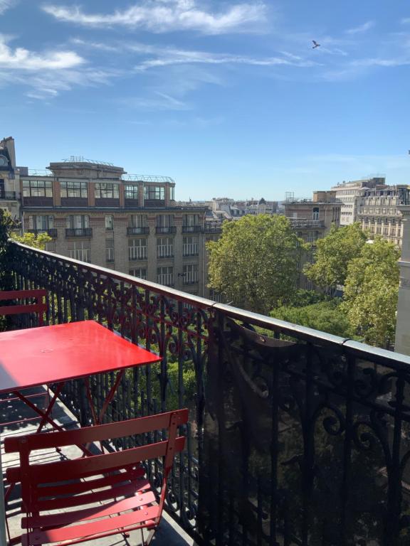 - un balcon avec une table rouge, des chaises et des bâtiments dans l'établissement Montmartre, à Paris