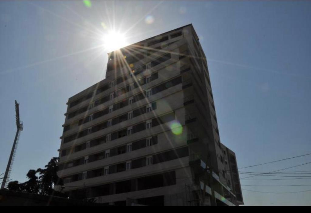 een hoog gebouw met de zon erop bij 12th floor one bed apartment in Elbasan