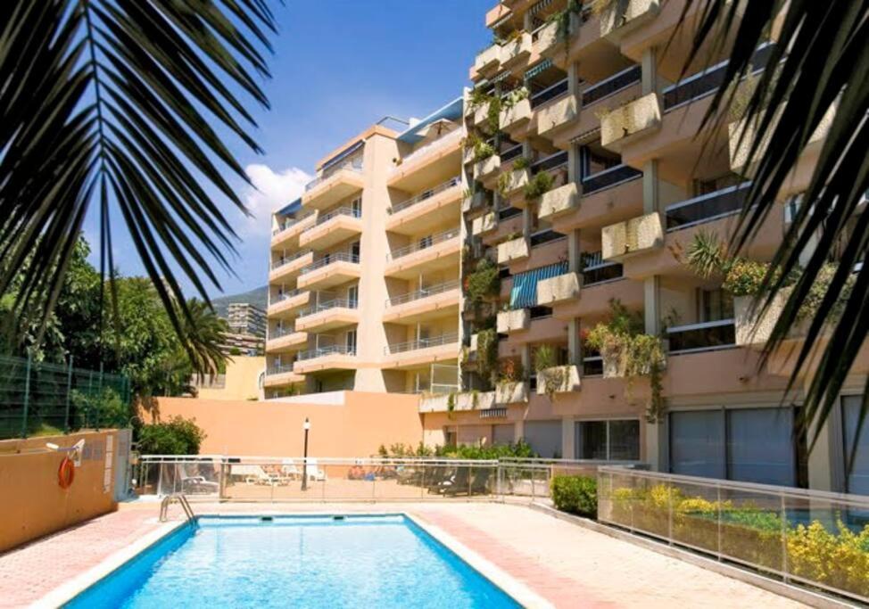a swimming pool in front of a building at Studio dans résidence avec piscine à 50m de la mer in Roquebrune-Cap-Martin