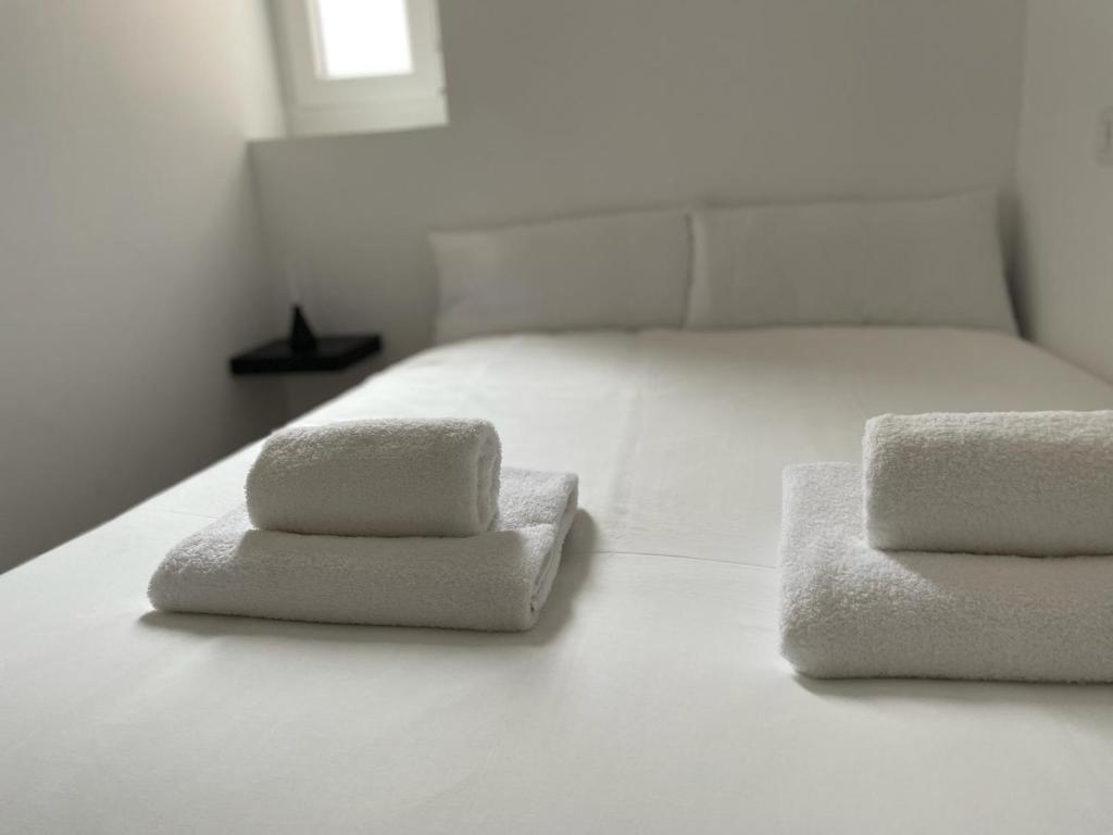two towels on a bed in a white room at Exyca Metropolitano in Madrid