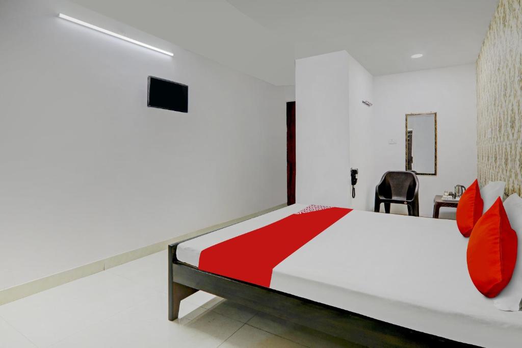 um quarto com uma cama com almofadas vermelhas e uma cadeira em OYO Flagship New Bhandan Lawn em Lucknow