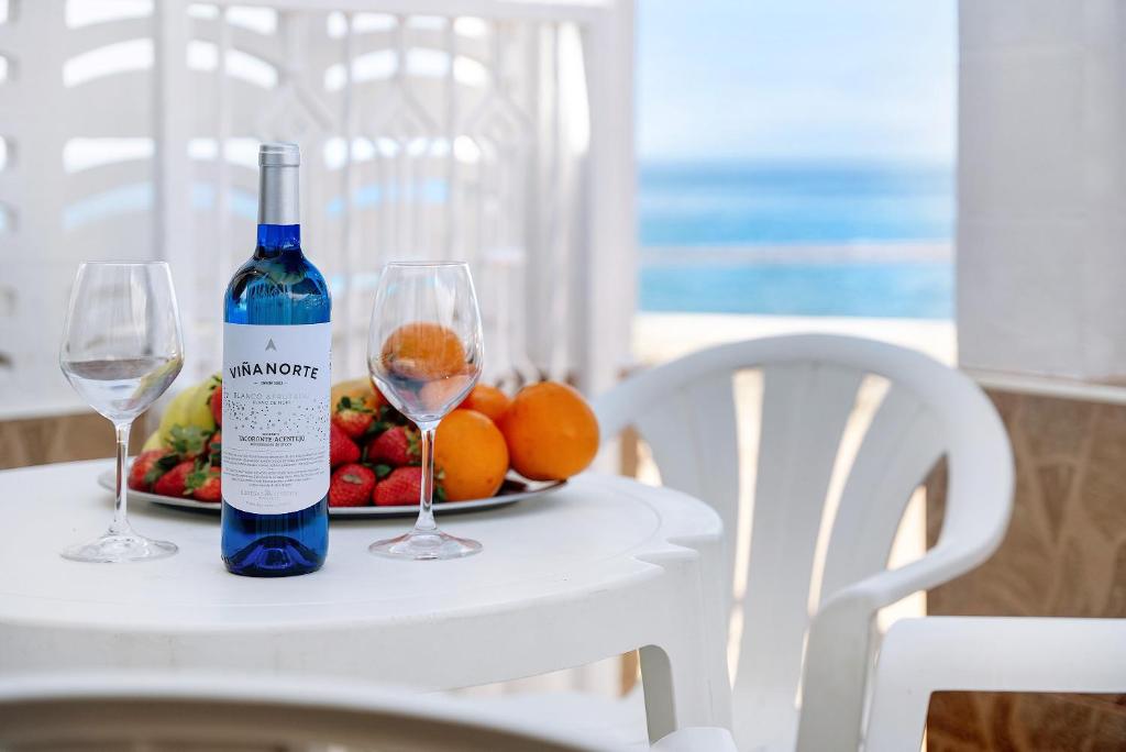 een fles wijn en twee glazen op een tafel met fruit bij Casa Pedro Julio Atlantic Sunset in Adeje