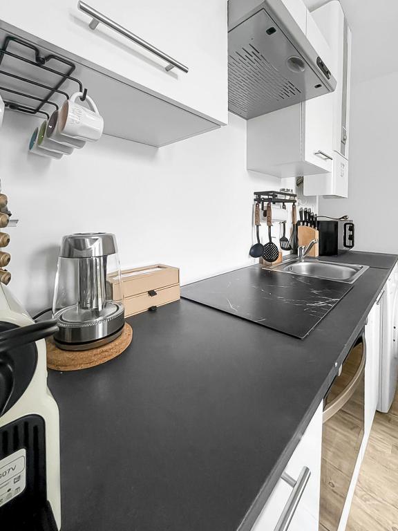 a white kitchen with a black counter top at Perle de la Loire in Blois