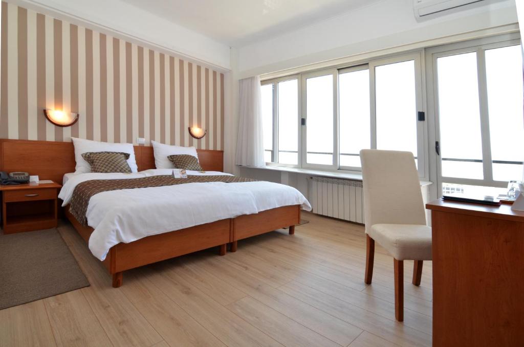 een hotelkamer met een bed, een bureau en ramen bij Hotel Neboder in Rijeka