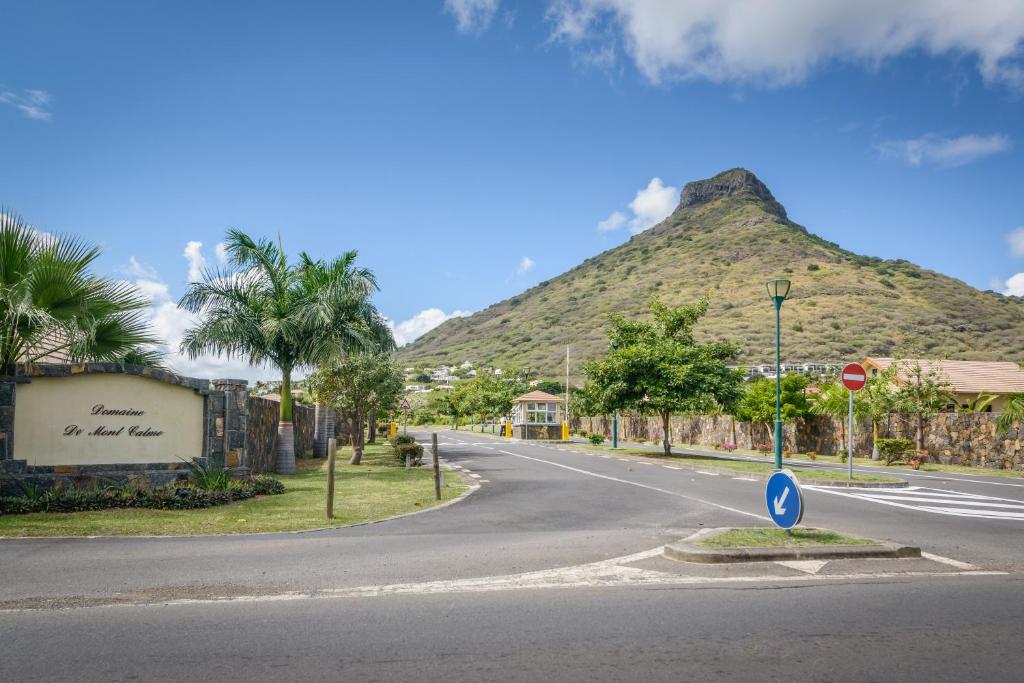 an empty street with a mountain in the background at West Coast Villas in Tamarin