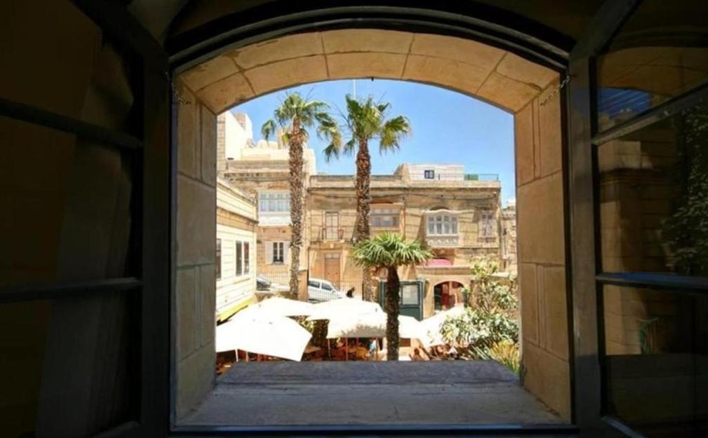an archway in a building with palm trees and umbrellas at Cittadella Boutique Living in Victoria