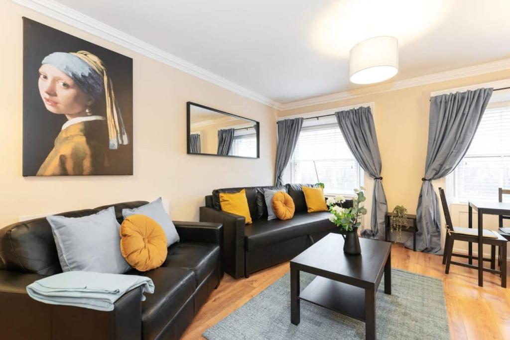 a living room with a black couch and a painting at Central 1BED APT RELIABLE FAST WIFI & TV in Dublin