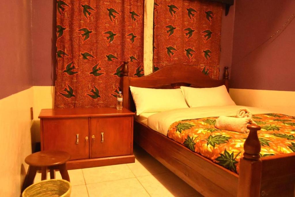 a bedroom with a bed with a wooden headboard and a chair at Room in BB - Amahoro Guest House - Single Room with Shower in Ruhengeri